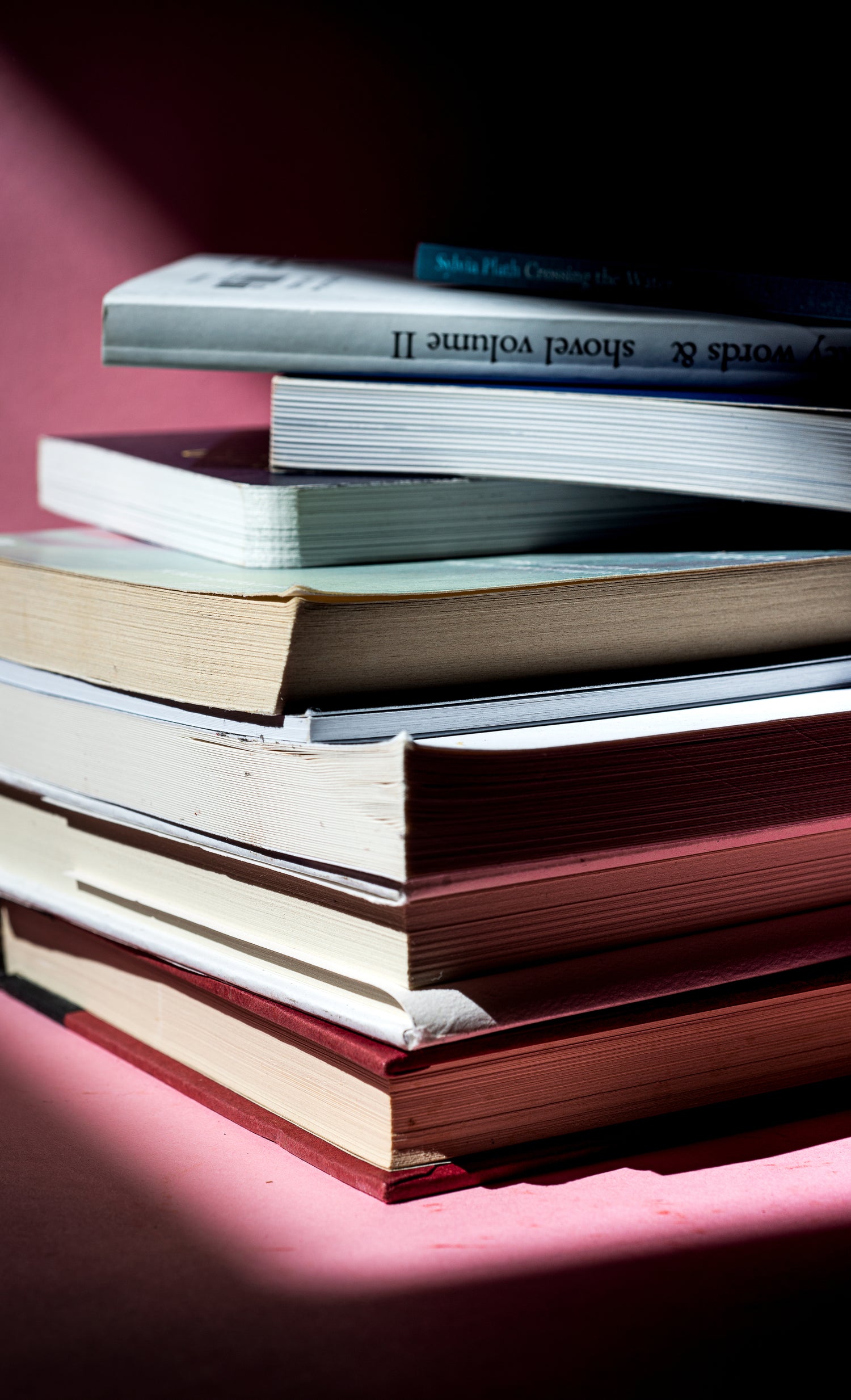 Close-up of a stack of books, showcasing their spines and covers in a cozy reading or study setting. This image evokes a sense of knowledge, relaxation, and a love for reading, perfect for illustrating educational themes, libraries, or home study spaces.