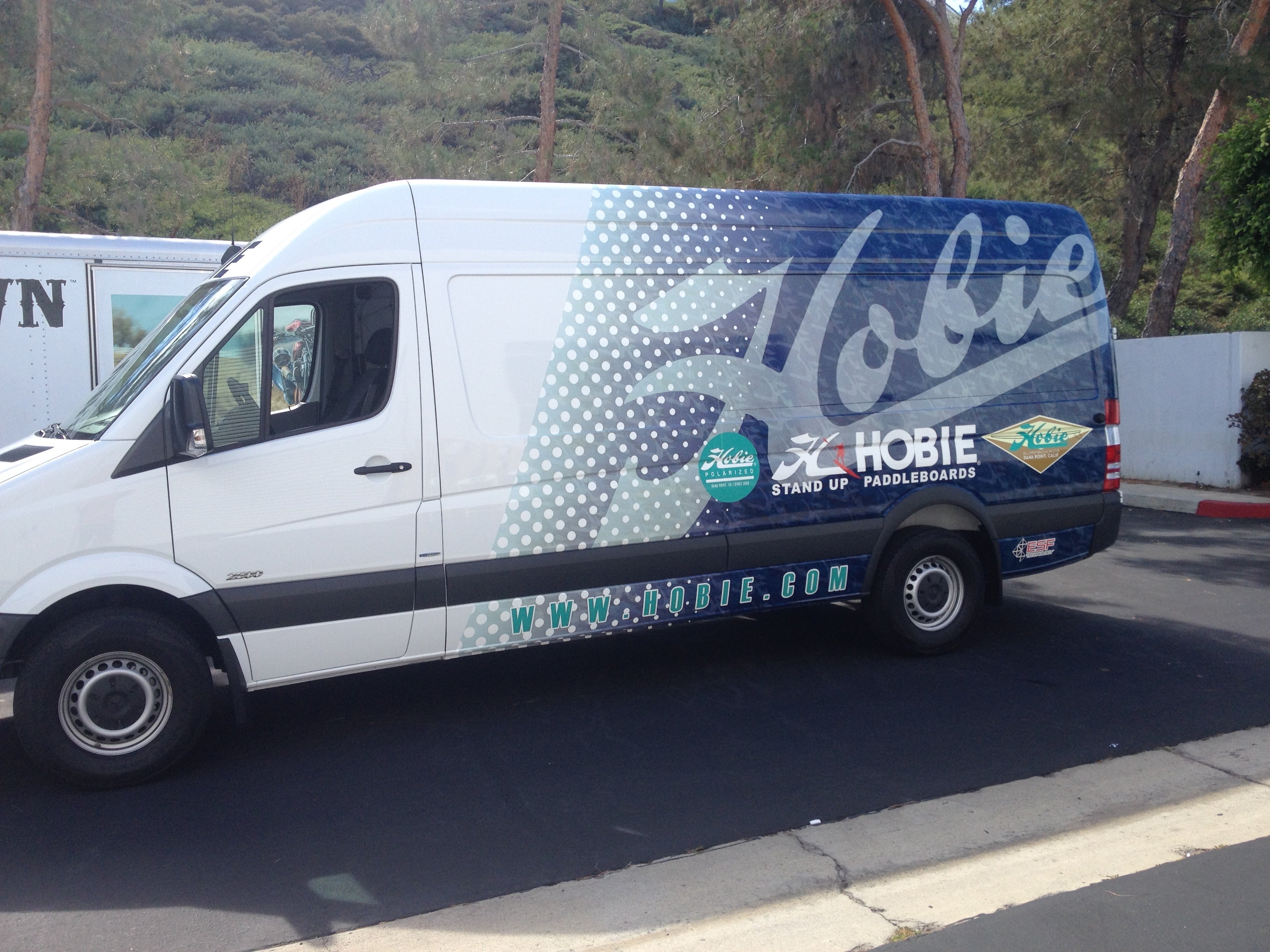 Side view of a custom wrapped cargo van, featuring vibrant and professional vehicle graphics. This custom wrap transforms the van into a mobile advertisement, promoting your brand and services while offering functionality for transporting goods and supplies. Perfect for businesses looking to maximize visibility on the road.