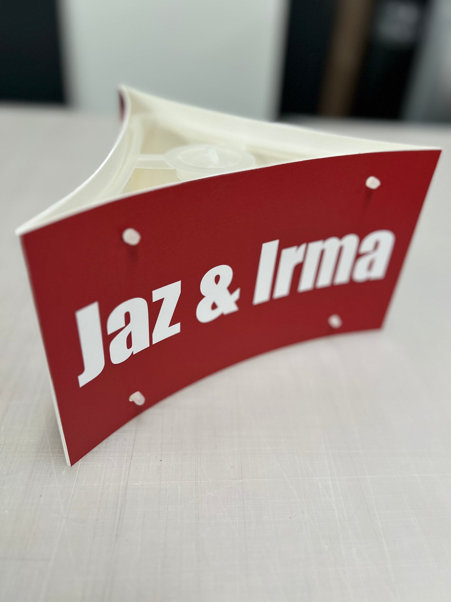Red sign with 'Jaz & Irma' text on a white surface