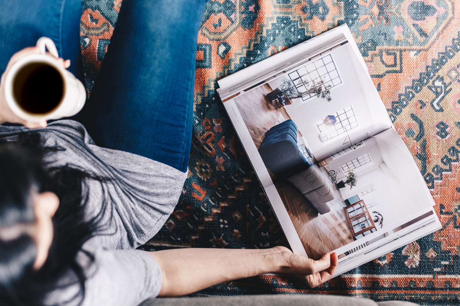 A woman enjoying a cup of coffee while reading a catalog, creating a relaxed and comfortable atmosphere. This image captures a peaceful moment of leisure, ideal for promoting catalogs, lifestyle, or consumer products, emphasizing a cozy and enjoyable experience.