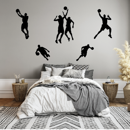 A vinyl decal of a basketball player in mid-dunk, applied on a wall in a gymnasium setting, with natural light falling on it.