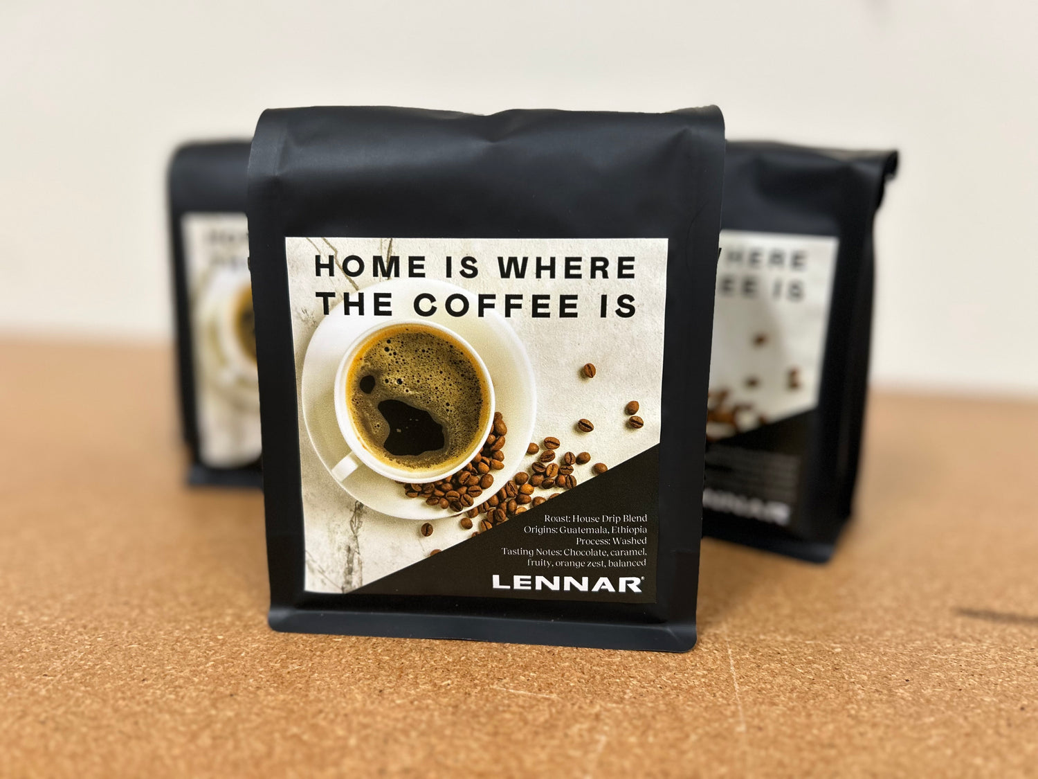 Black coffee packaging with a coffee cup and beans design, featuring the text 'Home is where the coffee is' and 'Lennar'.