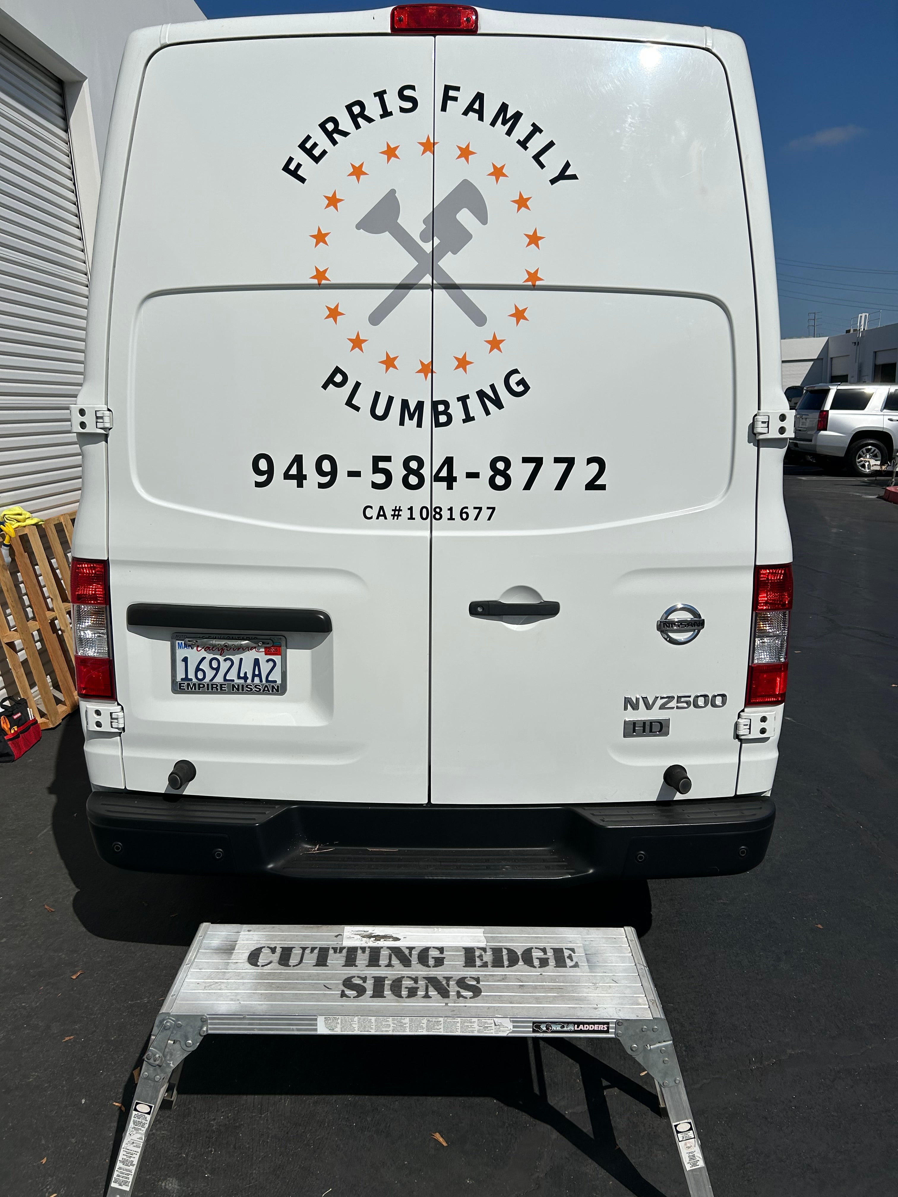 White van with plumbing company logo and contact information on a black surface