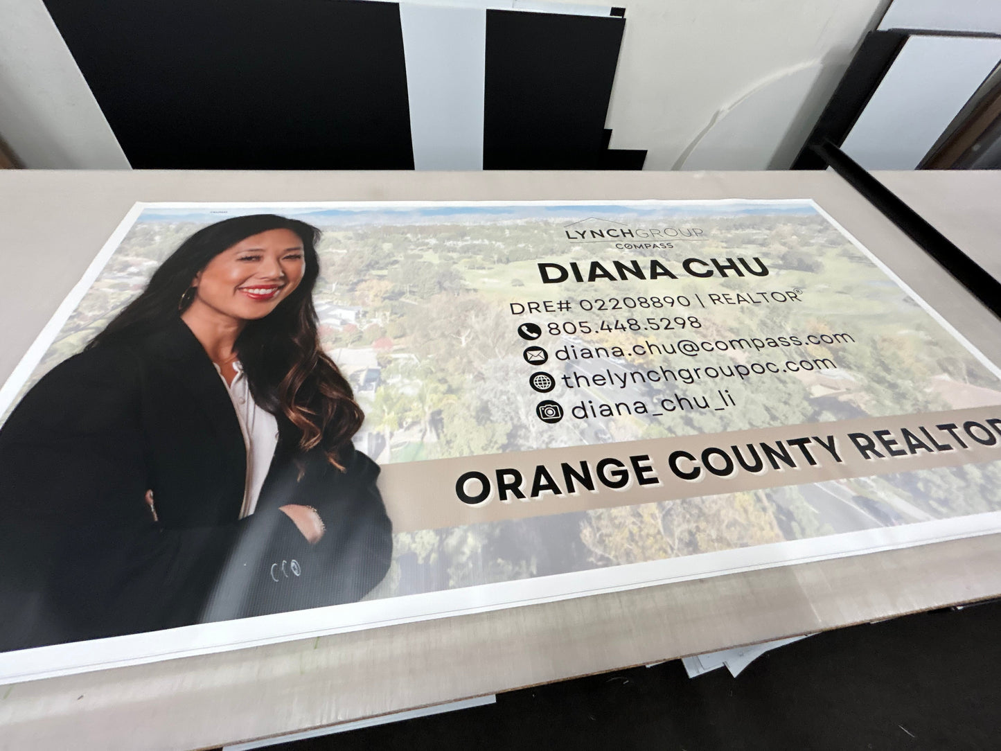 Real estate agent business card with a photo of a woman and contact information on a reflective surface.